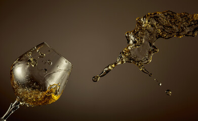 Glass and brandy splash on a brown background.