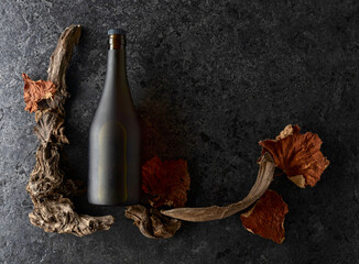 Bottle of brandy and old snags with dried up vine leaves.
