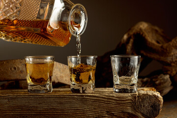 Whiskey is poured from a decanter into a shots.