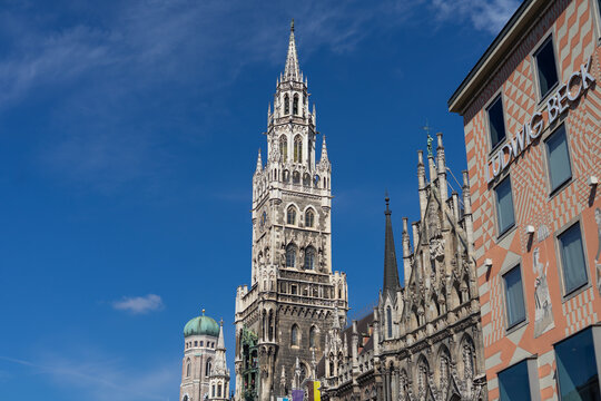 View of the New Town Hall and Frauenkirche dome on April 9, 2025 in Munich, Germany, showcasing Gothic revival architecture and bustling Marienplatz under a bright spring sky.