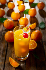 Orange juice and fresh fruits on an old wooden table.