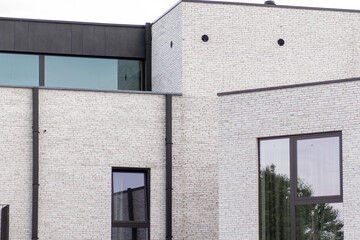 A fragment of a modern building featuring a grey brick facade. The minimalist architectural design highlights contemporary style and industrial aesthetics, modern construction