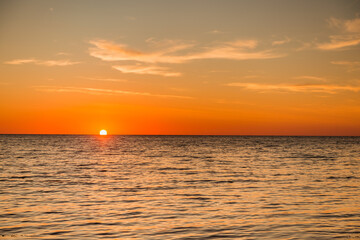 Sunset over the sea with orange sky and calm waves