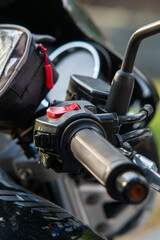 Motorcycle handlebar with prominent emergency kill switch
Close-up of the right motorcycle handlebar grip, focusing on the red emergency kill switch and control switches.