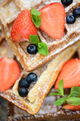 Delicious cake served with fresh strawberries and blueberries alongside crispy waffles.