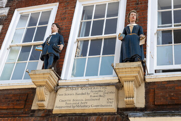 London, UK,  7 May 2025,  Bermondsey. two figures located on front of schoolhouse at St Mary Rotherhithe Free School, from 18th century.