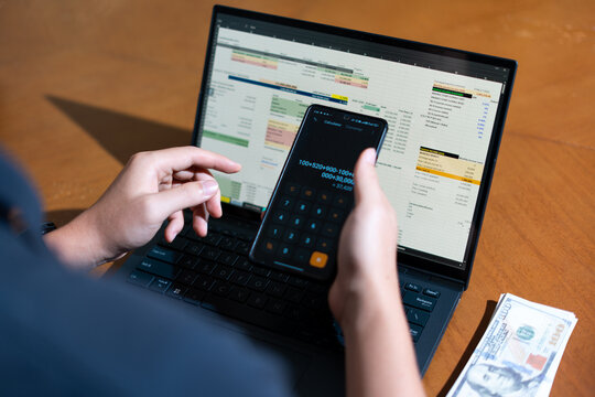 A person is using a calculator and laptop at the same time