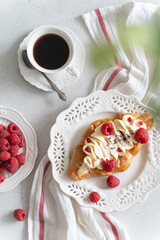 Trendy flat croissant on white plate, coffee. Delicious buttery thin croissant with fresh raspberry, cream. french breakfast. Viral Crusty flat croissant recipe, bakery, cafe menu, vertical top view