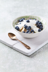 Healthy breakfast bowl with yogurt, blueberries and granola on a bright background. Copy space.
