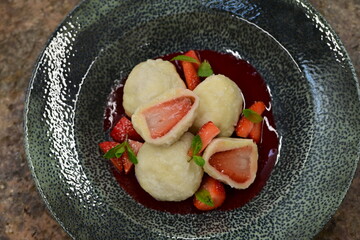 Close-up of traditional curd dumplings with strawberries – served with strawberry sauce and fresh mint.