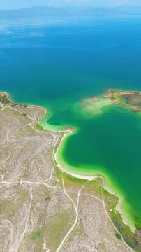 Scenic aerial drone image of a  island surrounded by white sand coastline. Chayei Island, Sevan, Armenia