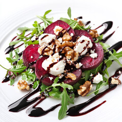 A roasted beet salad topped with goat cheese, arugula, walnuts, and a sweet balsamic reduction, served as a vibrant and healthy dish.