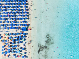 Summer vacation and rest. Beach, people and umbrellas. Top view from drone at the beach and azure sea. View on the coast from drone. Background, wallpaper, postcards.