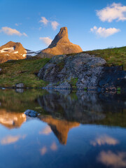 Norway. Mountain landscape. View of a high mountain in a valley. Huge sharp rocks and reflection on the water surface. Landscape in summer time. A place for trekking.