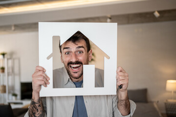 Excited man holding house sign showing enthusiasm for new home