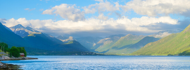 Norway. Nature in fjords. High mountains and reflections. Panoramic view. Clouds over the rocks. Vacation and travel in summer Norway. Background, wallpaper, postcards.
