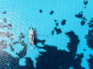 Summertime vacation. Drone view on the yacht. Sail yacht on the sea as a background. .Sea and waves from top view. Blue water background from top view. Top view from drone.
