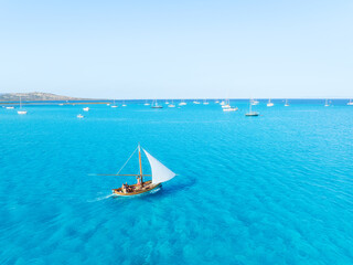 Summertime vacation. Sailing yacht at sea. Drone view on the yacht. .Sea and waves from top view. View on the coast from drone. Background, wallpaper, postcards.