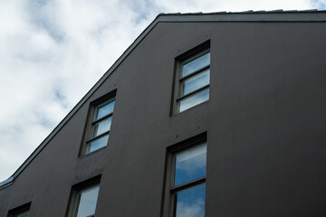 Modern Curved Building Facade with Grid Pattern Windows Reflecting Sky Clouds Low Angle View