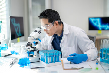 A man in a lab coat is looking at a microscope