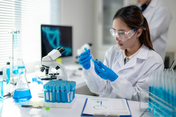 A woman in a lab coat is holding a test tube