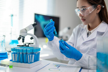A woman in a lab coat is holding a blue tube