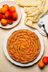 Apricot frangipane tart on a beige table surface. Directly above. Homemade bakery.