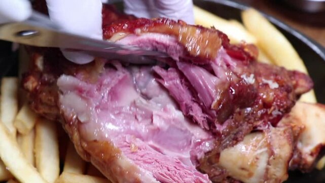Juicy pork being sliced with fries