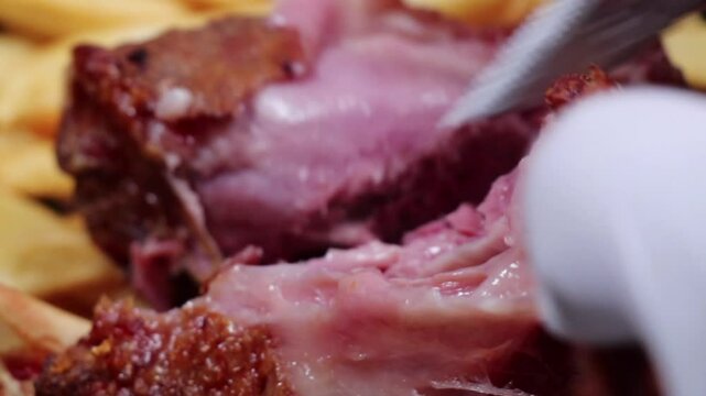 Juicy pork being sliced with fries