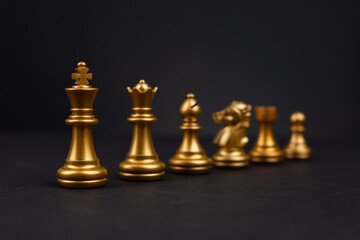 Gold chess piece stand in a row king, queen, bishop, knight, rook, pawn on black background