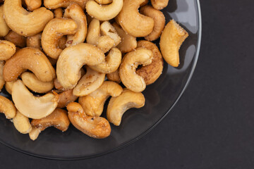 Top view of Roasted cashew nuts in glass bowl on dark background.