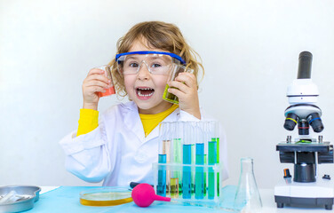 Laboratory examination of a child with test tubes, reagents and a microscope. Selective focus.
