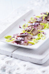 Sliced salted herring with leek and spices. Bright background.	