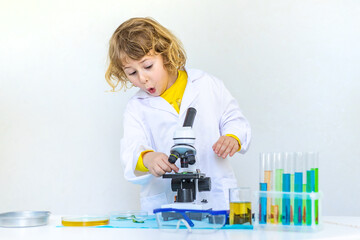 Laboratory examination of a child with test tubes, reagents and a microscope. Selective focus.