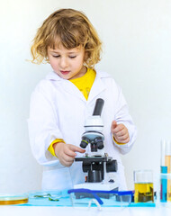 Laboratory examination of a child with test tubes, reagents and a microscope. Selective focus.