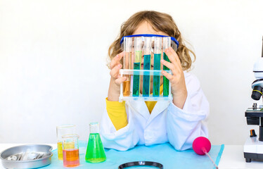 Laboratory examination of a child with test tubes, reagents and a microscope. Selective focus.