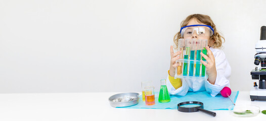 Laboratory examination of a child with test tubes, reagents and a microscope. Selective focus.