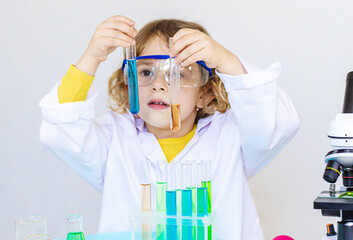 Laboratory examination of a child with test tubes, reagents and a microscope. Selective focus.