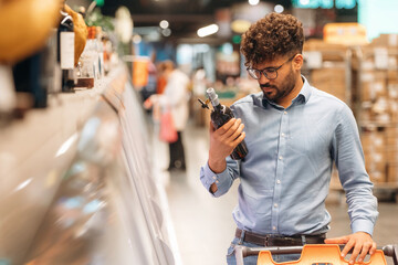 Bottle in hand. Man is in the grocery store