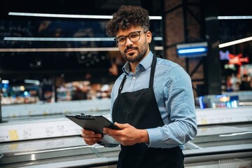 Fototapeta premium Manager is with notepad. Male worker is in the grocery store