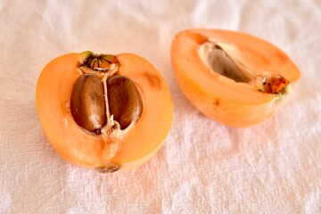 Single ripe loquat fruit on a table. Fresh and natural seasonal fruit with smooth skin and warm tone.