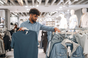 Sweaters section. Man customer is in the clothing store