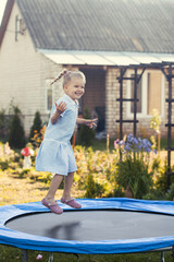 Little girl jumping on a trampoline on a summer day.
