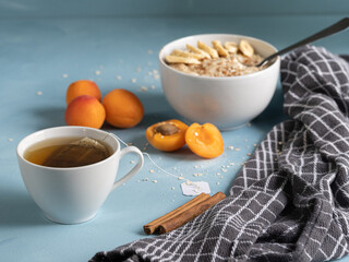 Healthy, vegetarian and energetic breakfast prepared on a blue background. Porridge with fresh fruit and tea