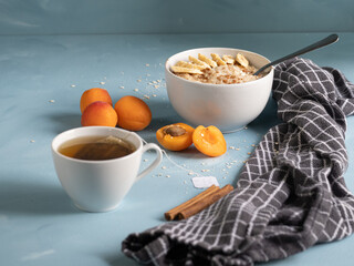 Healthy, vegetarian and energetic breakfast prepared on a blue background. Porridge with fresh fruit and tea