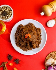 An authentic Indonesian Rendang dish that is delicious and aromatic, served with fresh spices such as garlic, shallots, chilies, and other herbs.