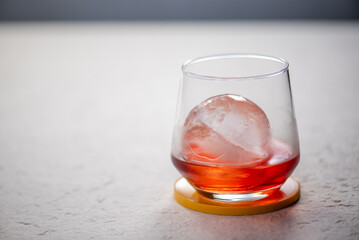 Closeup of a hand pouring sparkling water into a glass with red liquid and ice.