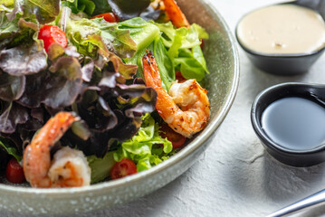 A bowl of shrimp salad with a side of dressing. A healthy and delicious meal.