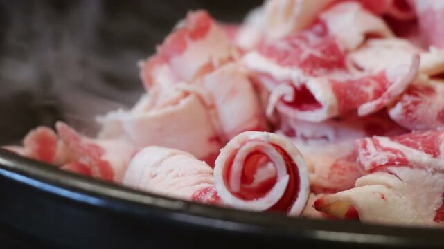 Thinly sliced meat being cooked in a pan