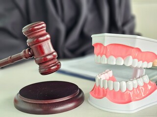 Courtroom setting featuring a gavel next to a dental model with human teeth during a law